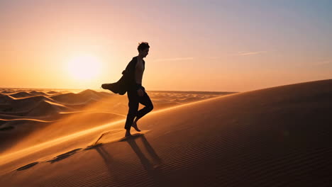 silhouette of a person climbing a sand dune in the desert at sunset