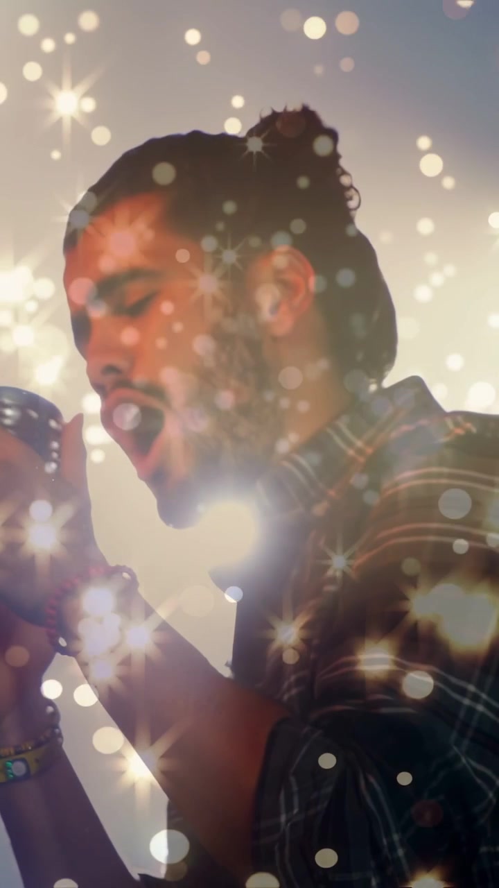 Vertical video: Singer leaning into vintage mic, starting vocal for music, rim bokeh rising, fading