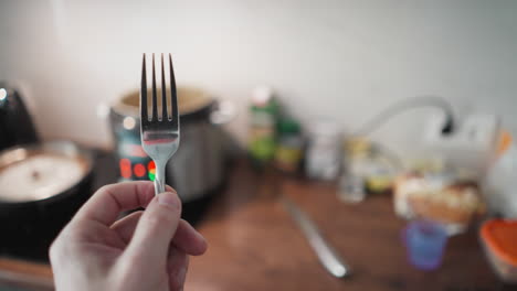 video de pov de mano de una persona girando un tenedor con las luces parpadeantes de una cocina múltiple en el fondo borroso