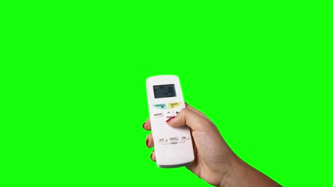 mujer con la mano usando un control remoto para cambiar la temperatura del aire acondicionado, tomada con fondo de pantalla verde. toma profesional en resolución 4k