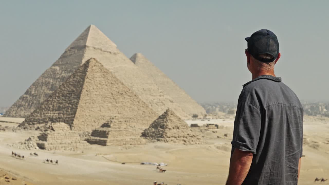 Uomo di spalle che guarda il leggendario Altopiano di Giza. Sono visibili tutte e tre le piramidi principali: la Grande Piramide di Cheope, la Piramide di Chefren e la più piccola Piramide di Micerino.