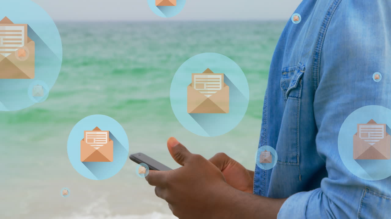 animación de iconos de correo sobre la sección media de un hombre biracial que usa un teléfono inteligente en la playa