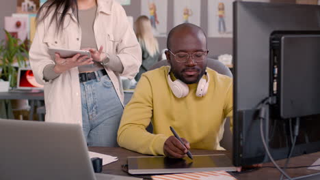 two multiethnic colleagues with tablets discussing a new project together in an animation studio