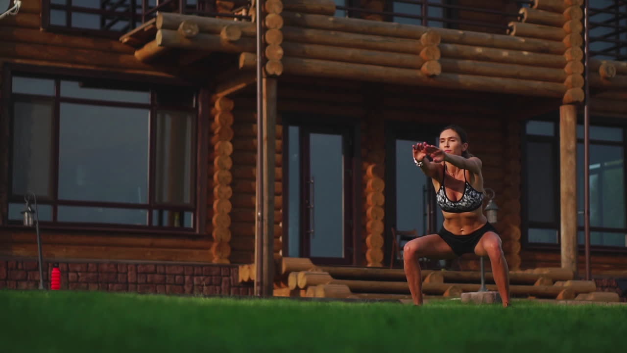 красивая брюнетка на фоне большого особняка, занимается в спортзале и выполняет приседания, упражнения на открытом воздухе, укрепляя мышцы бедер