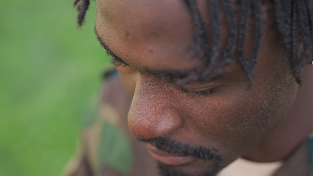 Black Soldier Praying Quietly With Clasped Hands In Camo, CloseUp Shows Bowed Head, Tense Fingers And Contemplative Expression In Green Backyard Intimate Moment Of Faith, Healing And Hope For Peace