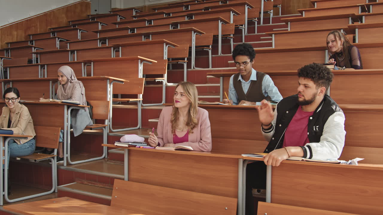 Male University Student Sleeping on Desk in Auditorium