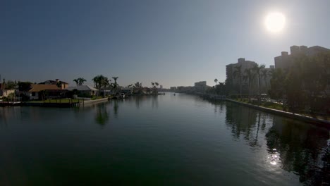 Aerial-4K-Drone-footage-flying-backwards-low-down-along-Vanderbilt-Channel-River-in-Naples,-Florida,-USA