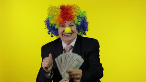 Elderly-clown-businesswoman-entrepreneur-boss-dancing,-entertains,-receive-money