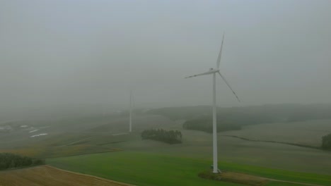 luftaufnahmen aus der nähe von windpark, windmühle bei nebel, graue landschaft drumherum, erneuerbare energie auf freiem feld, unten naturlandschaft, grüne energie ist wichtig