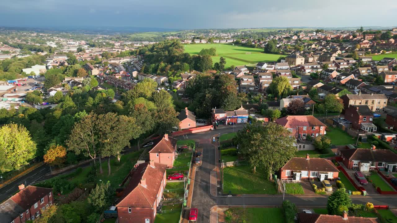 UK cityscape: Aerial view of Yorkshire's red brick council housing, bathed in morning sunlight, with homes and people on the streets