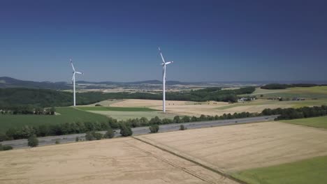 órbita-Aérea-De-Turbinas-De-Molinos-De-Viento-En-Campos-Agrícolas-Durante-El-Día-Generando-Energía-Renovable-Limpia-Para-El-Desarrollo-Sostenible