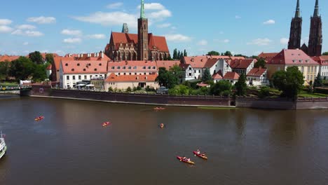 paddleboarders on river odra in wroclaw by cathedral island on beautiful sunny day - wrocław, poland
