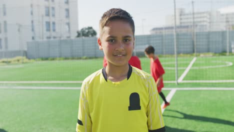 Mixed-race-soccer-kid-in-red-smiling-and-looking-at-camera