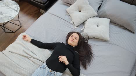 a woman rests on a cozy bed in a furniture store filled with lots of soft pillows a young woman rests peacefully on a cozy bed in a furniture store filled with lots of soft decorative pillows