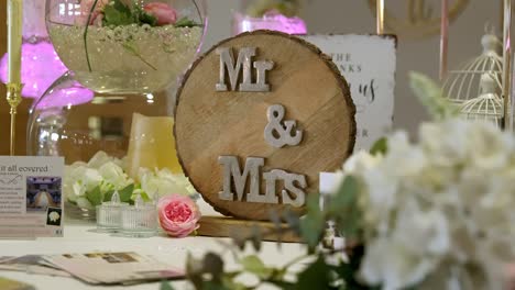 mr and mrs lettering on wooden sign placed on wedding table with beautiful white flowers and other decor.