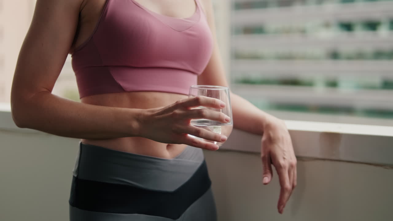 Donna in forma si idrata su un balcone in città