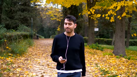 joven feliz y gracioso escuchando música y bailando en el parque