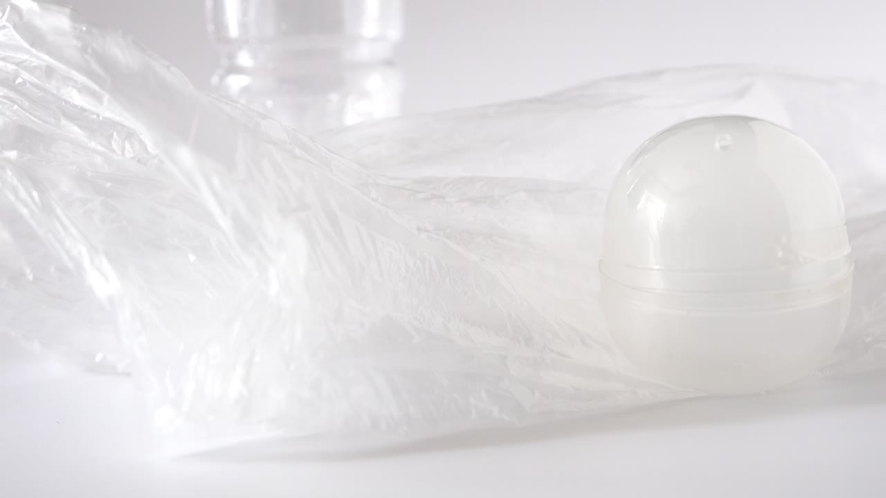 플라스틱 오염:병, 가방, 포크, 숟가락, 팩 및 곰팡이, 스튜디오 흰색 배경에서 하나씩 손으로 보여줍니다.