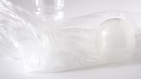 플라스틱 오염:병, 가방, 포크, 숟가락, 팩 및 곰팡이, 스튜디오 흰색 배경에서 하나씩 손으로 보여줍니다.