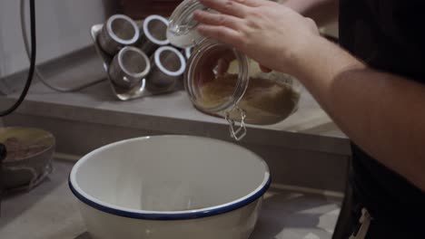 el chef vierte arroz del recipiente de vidrio en el plato hondo de cocción