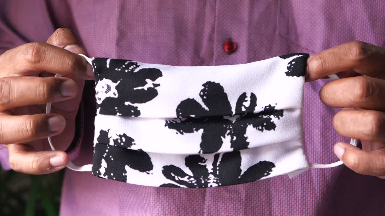 꽃 인쇄 천 마스크 를 들고 있는 사람