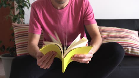 hombre con un libro en sus manos, lo abre y deja pasar las páginas