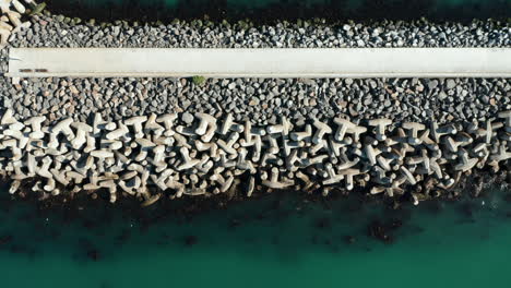 mound seawall built with concrete tetrapod-shaped rocks at the seaport of cape town, south africa