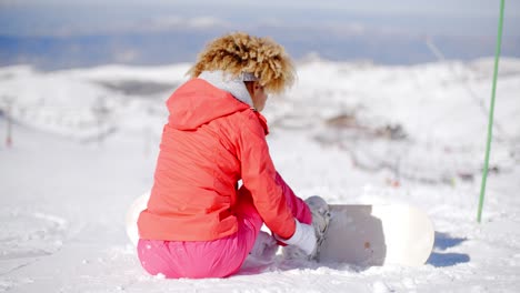 Woman-putting-a-snowboard-on-her-boots