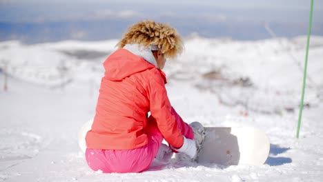 woman putting a snowboard on her boots