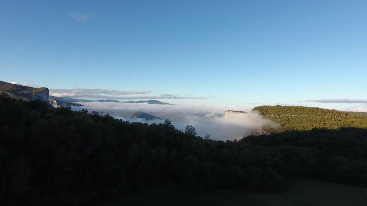 un disparo aéreo de un dron volando hacia las montañas nubladas de vercors. un amanecer místico.