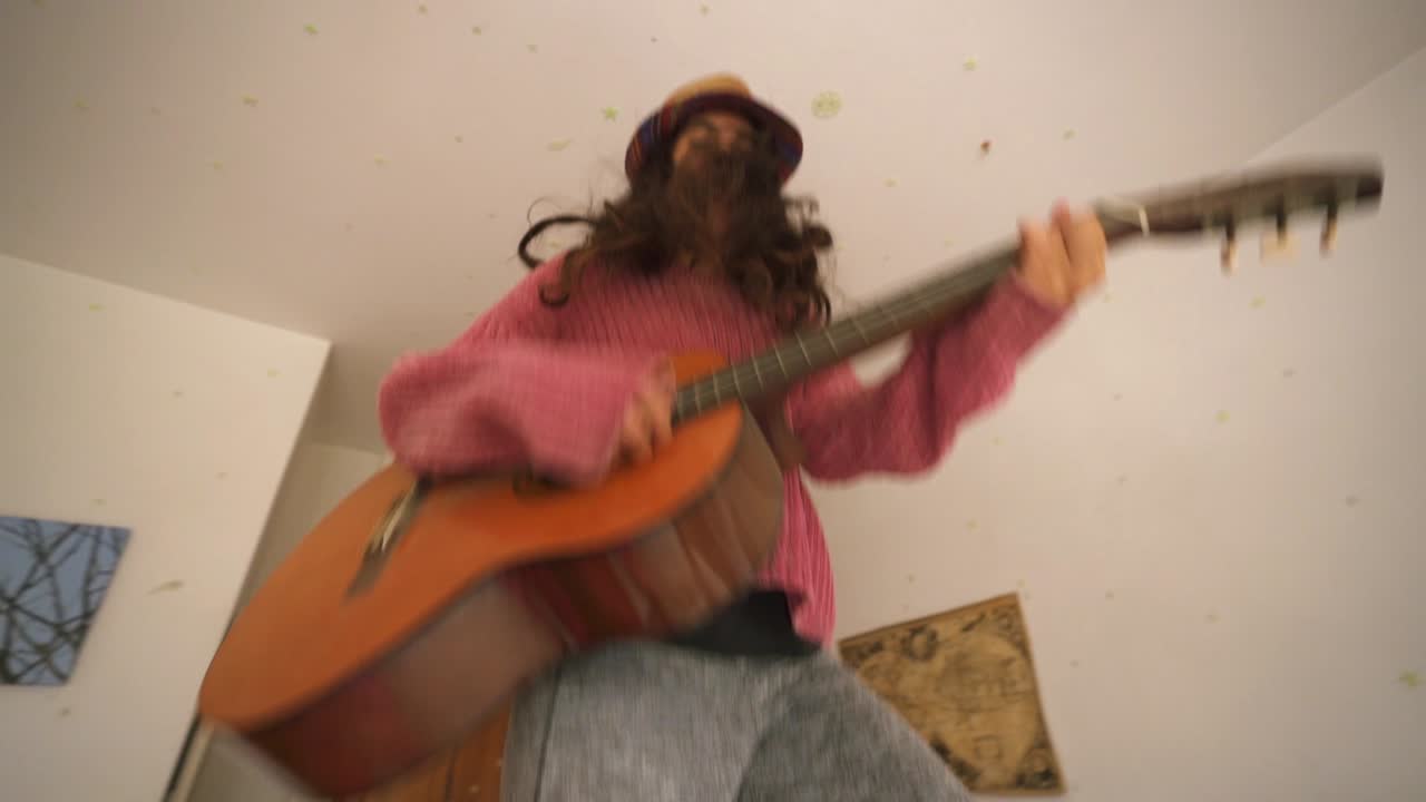 Ung pige hopper på seng med guitar i soveværelse derhjemme