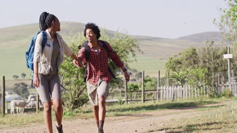 Happy-african-american-couple-with-backpacks,-hiking-together-on-sunny-day,-slow-motion