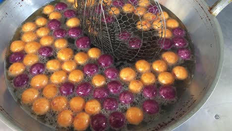 cooking quail candy eggs or turtle eggs sweets in big pan with hot oil, thai traditional dessert snack made from cassava flour (tapioca starch) and sweet potato at the market. 4k footage.