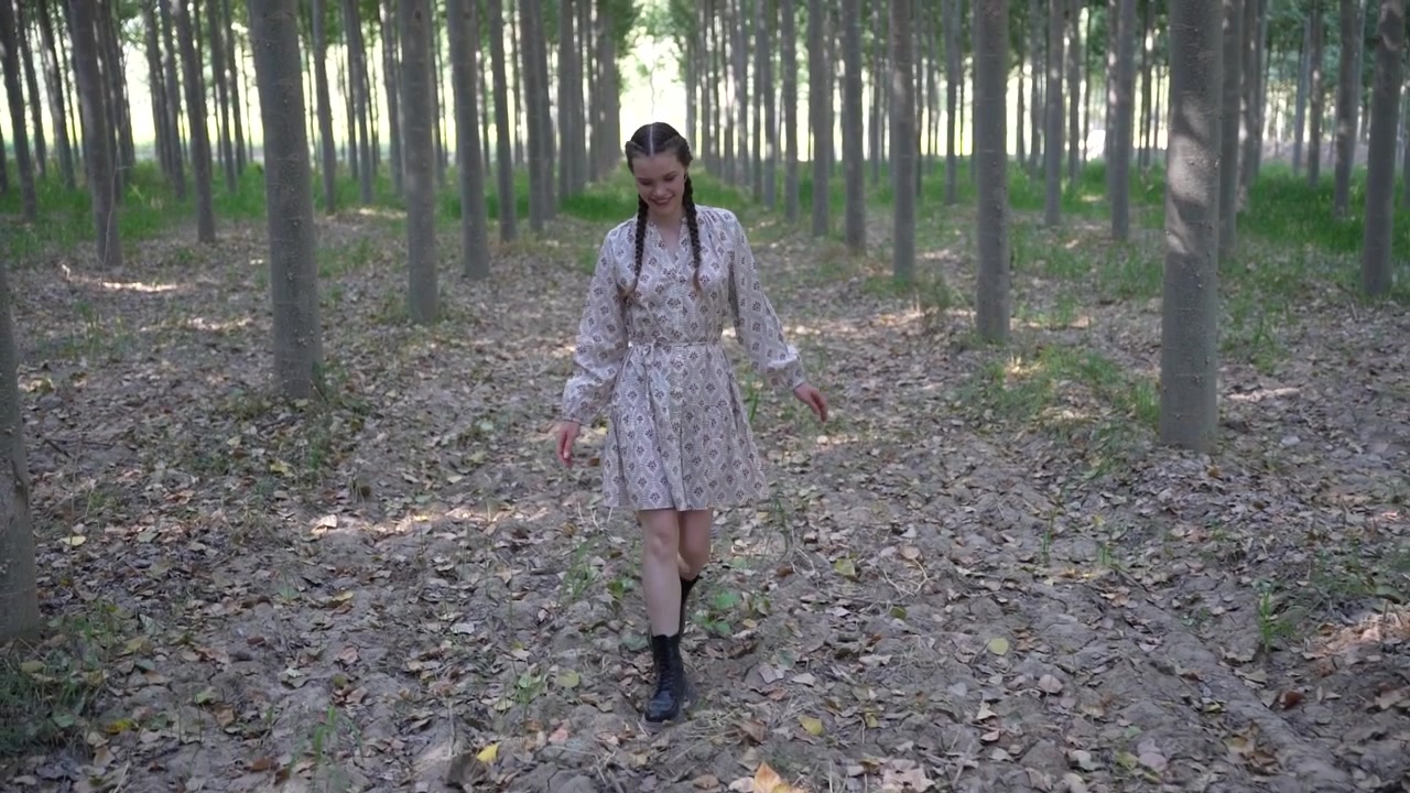 Una ragazza gioiosa che balla con grazia su un bellissimo e sereno sentiero nel bosco, circondata dalla natura.