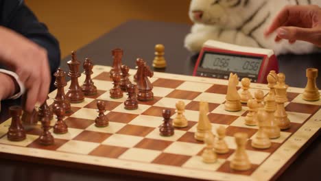 chess grandmasters playing speed chess with a chess clock and a wooden chessboard