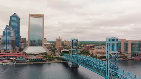 view of the blue jacksonville bridge and buildings at the riverfront with white clouds covering the sky