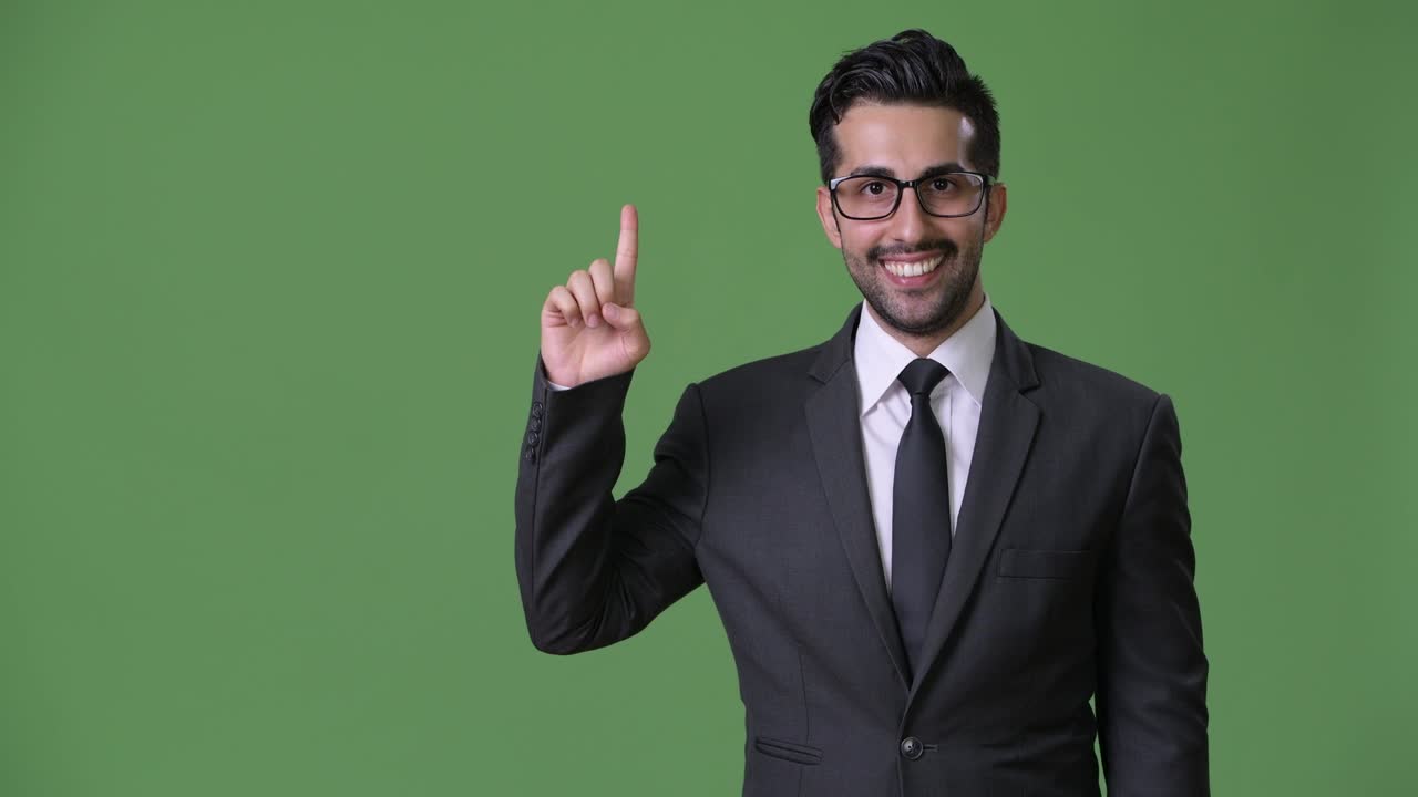 joven empresario persa barbudo y guapo contra un fondo verde