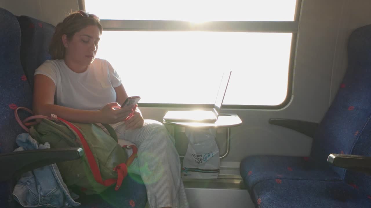 Sun Flare Highlights a Woman Using Her Phone on a Train