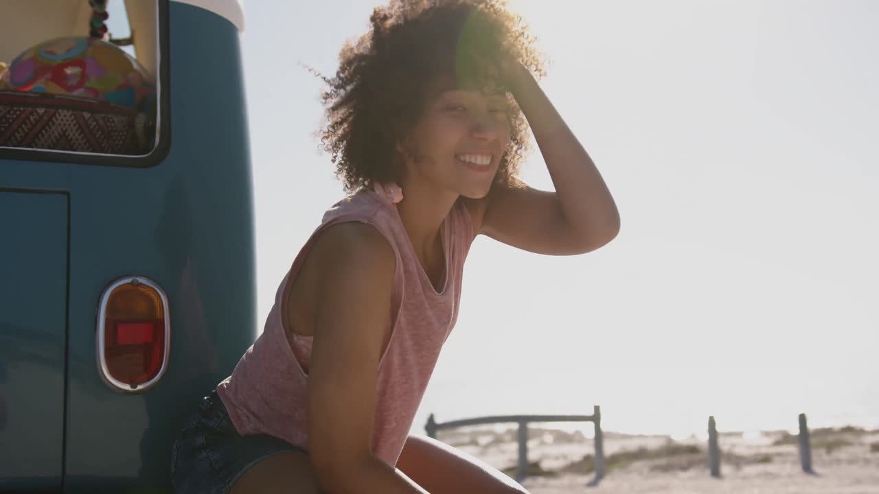 Young woman sitting by camper van at a beach 4k