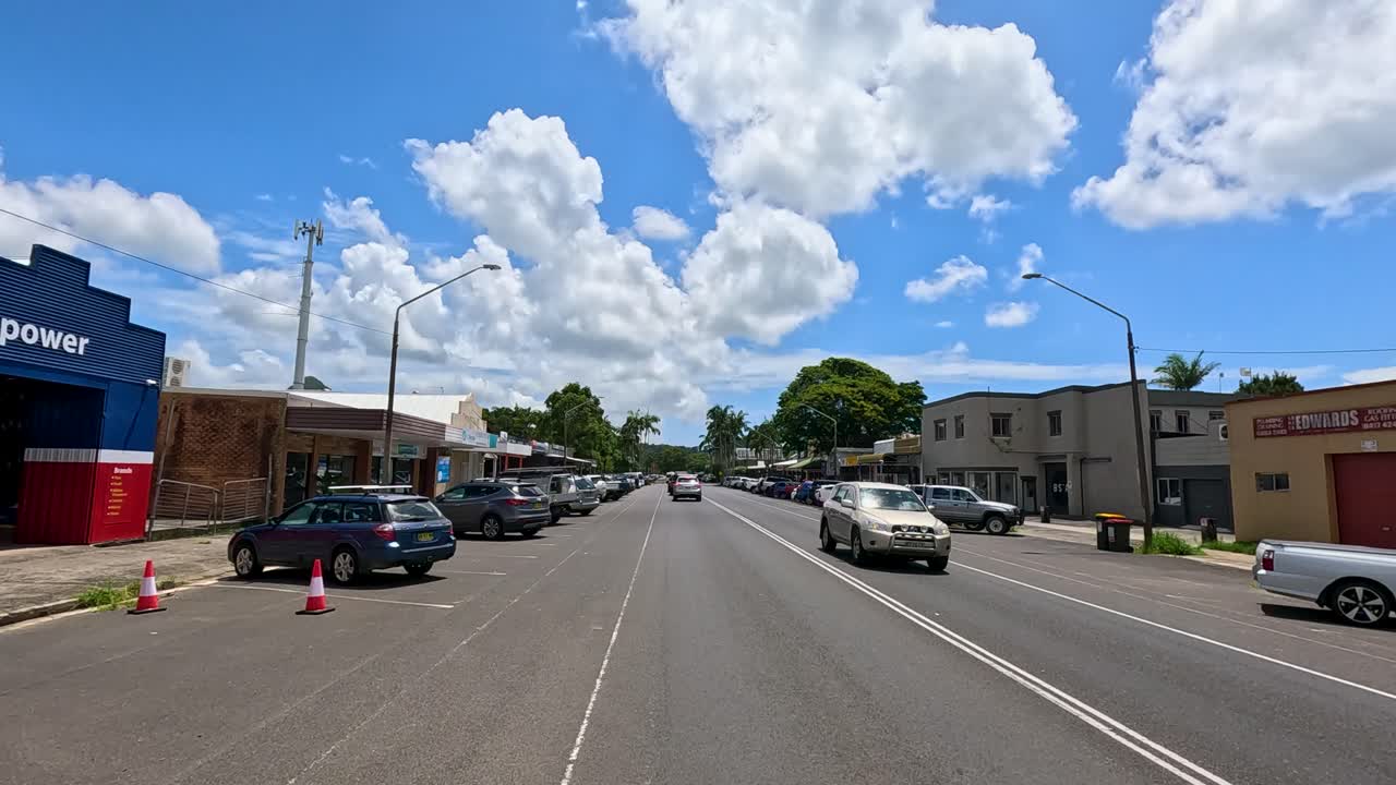 A bustling street in Mullumbimby, NSW, with cars and shops under a bright blue sky