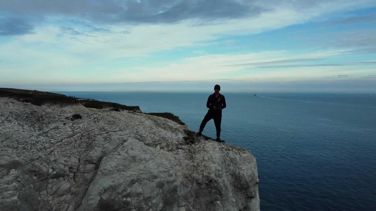 hombre de pie en un acantilado con vistas al océano