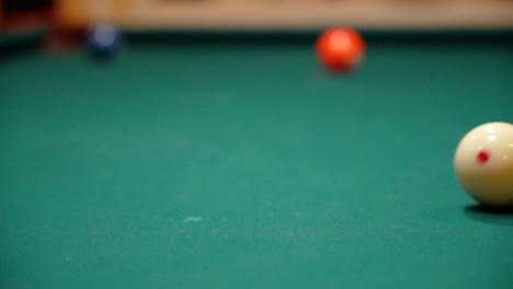 slow motion billiards white cue ball rolls across pool table with green felt close up from a low angle