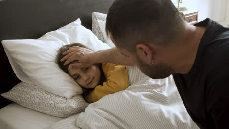 solicitous father checking forehead of sick daughter.