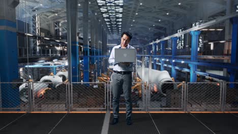 full body of an asian male professional worker standing with his laptop at the center of the wind turbine factory, he is nodding his head with dissapionted