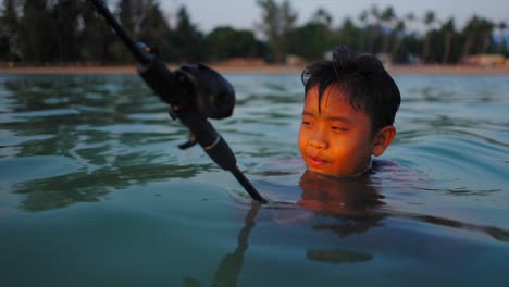 young boy fishing in the sea during golden hour