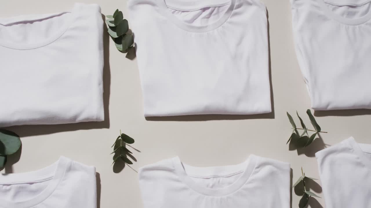 Video of flat lay of folded white t shirts with copy space on white background