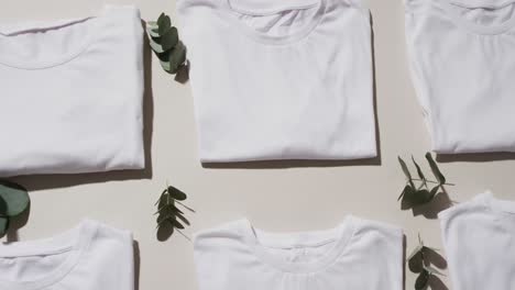 Video-of-flat-lay-of-folded-white-t-shirts-with-copy-space-on-white-background