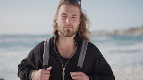 retrato de un atractivo hombre caucásico en la playa mirando a la cámara serio relajado hombre rubio verano cálido fondo costero