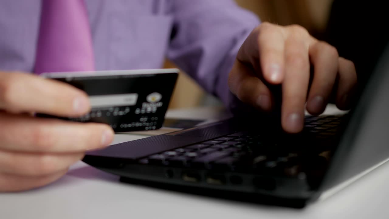 un hombre de negocios con una camisa púrpura y corbata está haciendo un pago a la banca por internet. compras en línea con tarjeta de crédito en la computadora portátil.