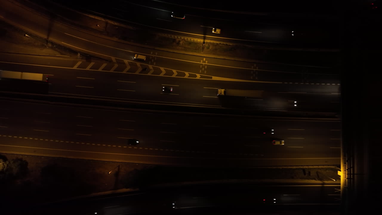 faros de tráfico iluminados conduciendo a lo largo de una autopista concurrida por la noche, vista aérea de pájaro